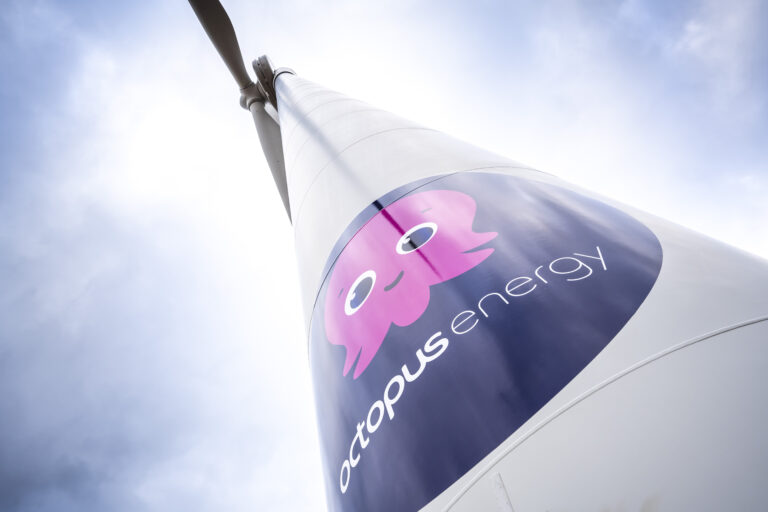 A photo looking up at an Octopus branded wind turbine.